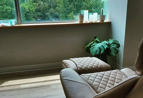 Image shows a relaxing view of nature, a recliner, and a verdant plant in our community acupuncture clinic