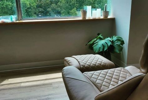 Image shows a relaxing view of nature, a recliner, and a verdant plant in our community acupuncture clinic